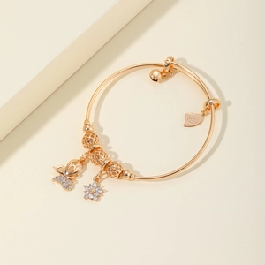Elegante brazalete dorado con mariposa y colgante de corazón en un fondo minimalista
