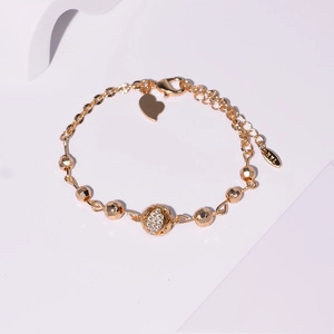 Détail du bracelet plaqué or avec une boule sertie de zircons et pendentif cœur