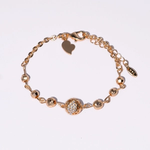 Détail du bracelet plaqué or montrant la boule sertie de zircons et le pendentif en forme de cœur