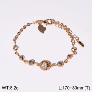 Détail du bracelet doré avec perle creuse sertie de zircons et breloque en cœur