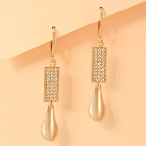 Macro detail of gold-plated lever-back earrings with cubic zirconia stones and metal drops