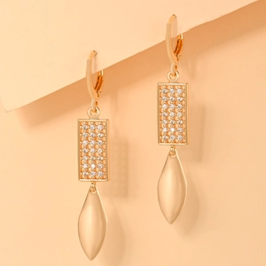 Close-up of gold-plated earrings with rectangular cubic zirconia and leaf-shaped pendants