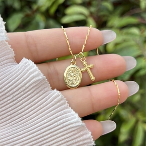 Detail of 18K gold-plated necklace with religious relief medallion and small cross charm