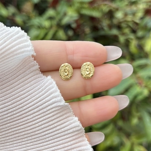 Detail of 18K gold-plated oval Guadalupe stud earrings with embossed religious design