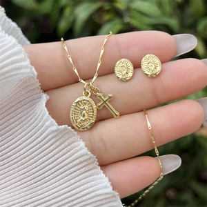 Close-up of 18K gold-plated cross and religious medallion necklace with oval earrings