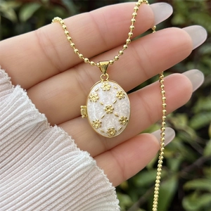 Détail d'un médaillon plaqué or 18 carats avec motif floral sur nacre blanche