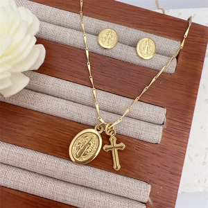18K gold plated cross and medal necklace set with matching stud earrings on display