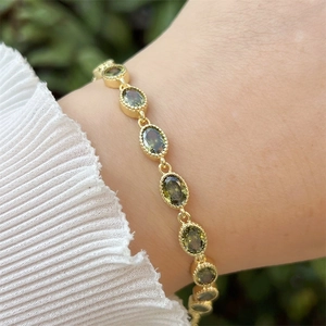 Detail of 18k gold plated bracelet featuring emerald green oval cubic zirconia stones