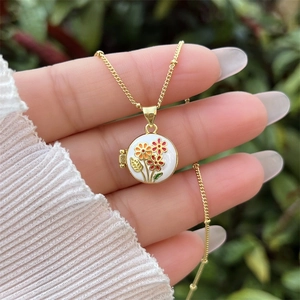 Detalle del relicario de flor bañada en oro de 18K con motivos florales de esmalte