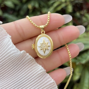 Macro-opname van gouden ovale medaillon ketting met sterpatroon en witte zirkoon inlay