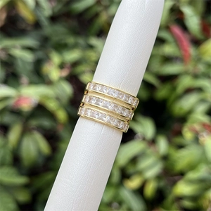 Macro shot of three stacked gold rings with square zircon stones on a ring mandrel