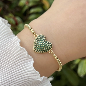Detalle de una pulsera bañada en oro de 18k con colgante de corazón de circón verde