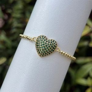 Detalle de la pulsera de cuentas bañada en oro de 18k con dije de corazón verde zirconio
