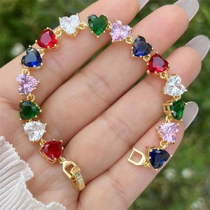Detail eines 18K vergoldeten Herzarmbands mit bunten Zirkonsteinen auf der Hand