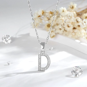 Dettaglio macro del ciondolo lettera D in argento con zirconi scintillanti su una catena