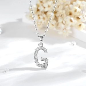 Dettaglio del ciondolo a forma di lettera G in argento con pavé di zirconi scintillanti