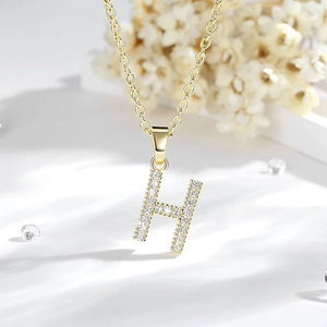Primo piano del ciondolo lettera H in oro 14K con zirconi su una catenina classica