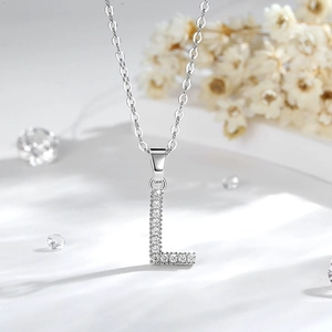 Dettaglio macro del ciondolo lettera L in argento con zirconi su una catena a O