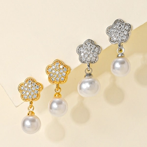 Detailed macro view of gold and silver flower pearl earrings with sparkling zircon inlay