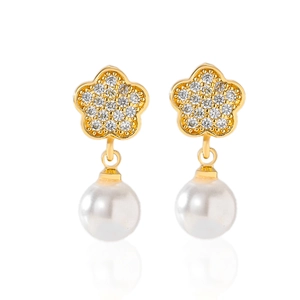 Detailed close-up of gold flower earrings with pavé crystals and round white pearls