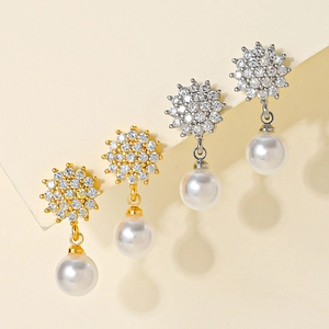 Detailed view of elegant starburst earrings with sparkling zircon and white pearl drop