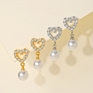 Detail of heart stud earrings with cubic zirconia and round white hanging pearls