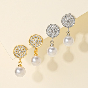 Detail of round gold and silver earrings with micro-pave cubic zirconia and white pearls