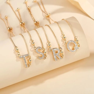 Adjustable gold plated letter bracelet with zirconia inlay featuring TS R Q charms