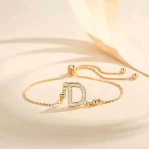 Macro shot of gold-plated bolo bracelet with zircon-encrusted letter D and adjustable chain