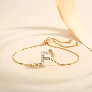 Macro detail of gold-plated letter F pendant with zircon pavé and adjustable chain