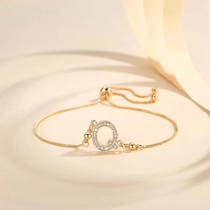 Detail of gold-plated bracelet featuring a zircon-encrusted letter Q with adjustable slider