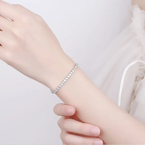 Elegantes silbernes Tennisarmband mit Zirkonia, am Handgelenk vor weißem Stoff getragen