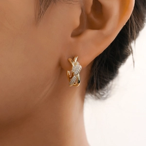 Boucles d'oreilles créoles croisées dorées avec pavé de cristaux sur un mannequin