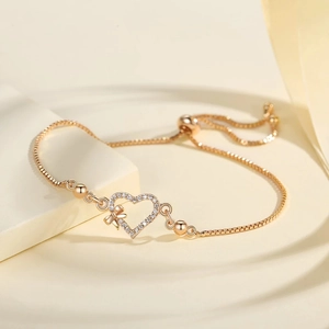 Detail of adjustable gold-plated heart bracelet with sparkling pavé zircons and bow design