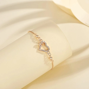 Rose gold heart bracelet with sparkling zircon pavé and bow detail on a silk backdrop