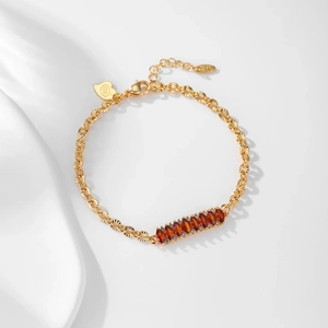 Detailed close-up of 14K gold plated bracelet with amber stones and heart tag