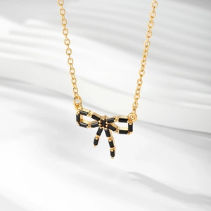 Détail d'un collier nœud plaqué or serti de pierres de zircone noires scintillantes