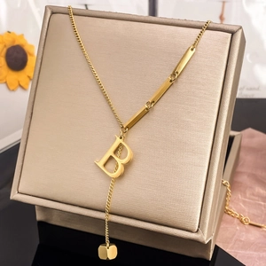 Y-shaped gold letter B pendant necklace with tassel chain on a display stand