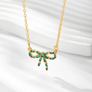 Vue détaillée du collier avec pendentif nœud doré et pierres de zircon vert émeraude