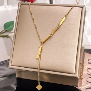 Detail of gold-plated Y-necklace with capital letter I pendant and tassel accents