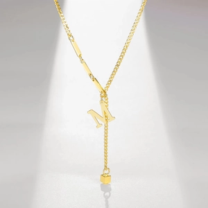 Detailed shot of golden alphabet M pendant necklace with long bar links and square charm