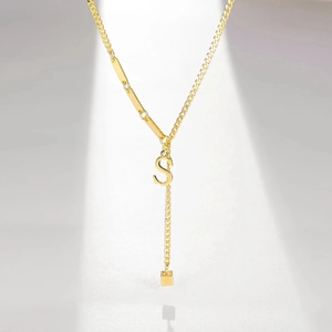 Detailed view of gold-plated Y-necklace with tassel and initial S letter pendant
