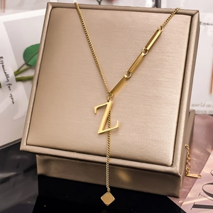 Detail of gold letter Z pendant necklace with asymmetric chain and steel tag