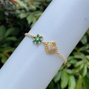 Elegant 18K gold-plated bracelet with emerald starburst and diamond-set heart pendants