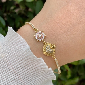 Detailed shot of 18K gold plated bracelet with pink flower and heart charms on wrist