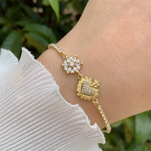 Detailed view of an 18K gold plated bracelet with zircon flowers and heart charms on wrist
