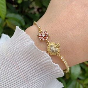 Close-up of 18K gold-plated bracelet with red zircon flower and crystal heart charm