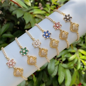 Macro view of floral and heart-shaped charms with colorful zircons on 18K gold plated bracelets