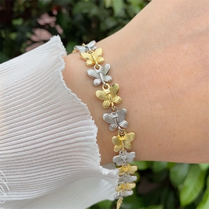 Élégant bracelet papillon bicolore plaqué or 18 carats sur le poignet d'une femme