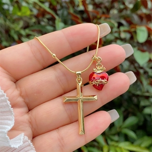 Detail der 18K vergoldeten Kreuz- und roten Herzanhänger an einer Schlangengliederkette